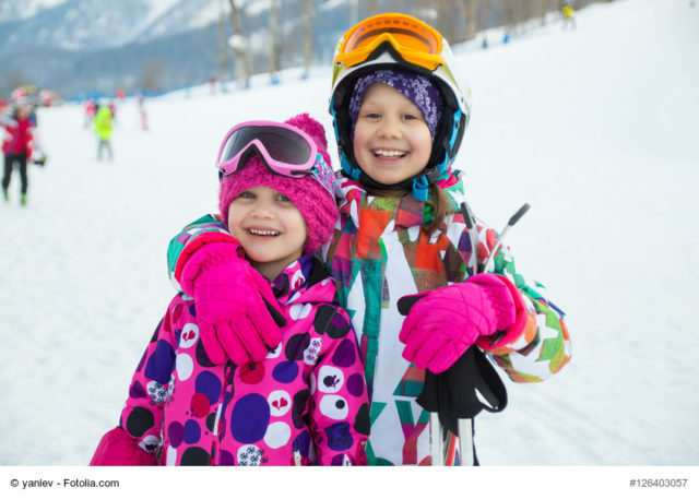 kinder im schnee, lachen und zeigen ihre zähne beim skifahren
