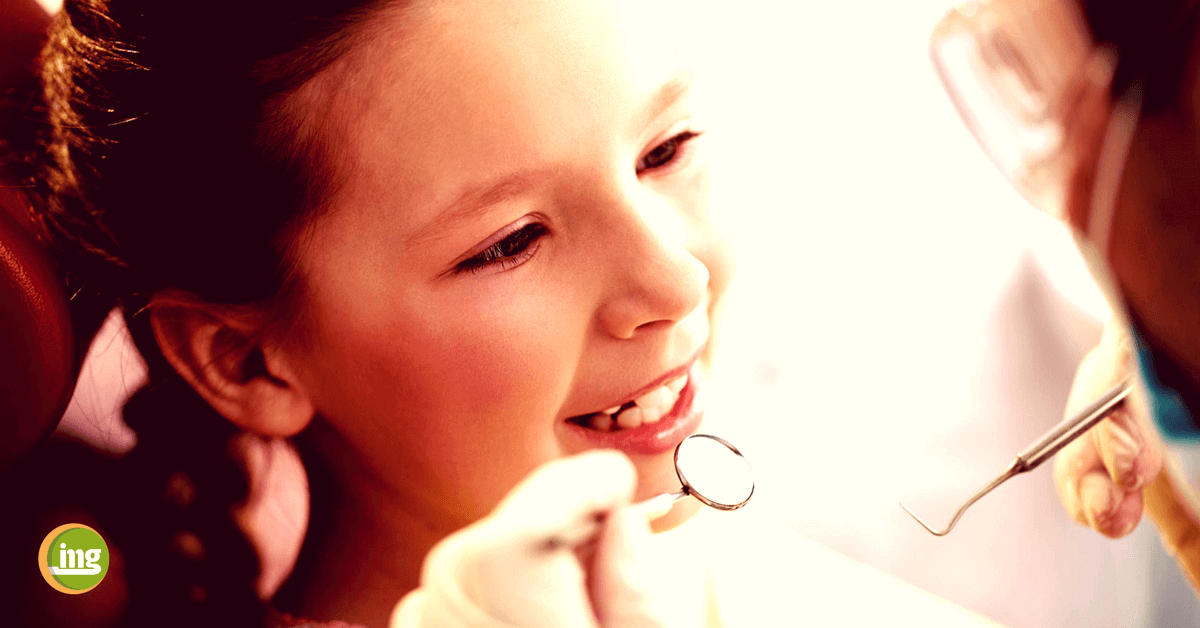 Zahnärztin untersucht Mädchen auf die Molaren-Inzisiven-Hypomineralisation (MIH). Ihre Zähne sind viel empfindlicher und anfälliger für Erkrankungen wie Karies. Information Mundgesundheit erklärt, wie MIH entsteht und was der Zahnarzt tun kann.