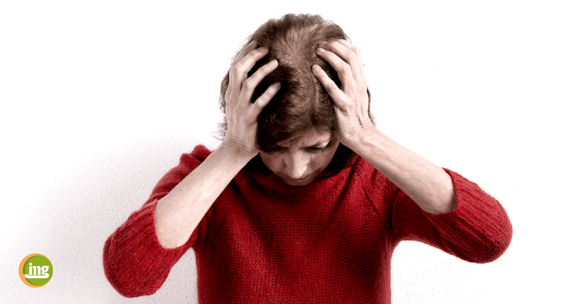 Frau in rotem Pullover hält sich den Kopf. Information Mundgesundheit berichtet zum Tag gegen den Schlaganfall über Parodontitis als Risikofaktor für Gehirn und Herz.