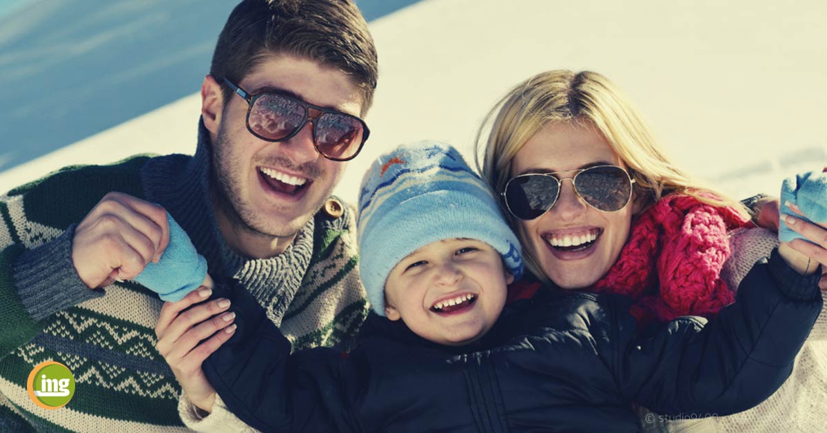 Junge Familie mit Kind im Schnee. Information Mundgesundheit berichtet über Zähne, Kälte und wie man sich vor Zahnschmerzen schützen kann.