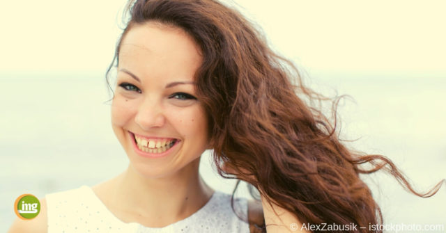 Junge Frau lächelt mit Zahnlücke zwischen den vorderen Schneidezähnen.