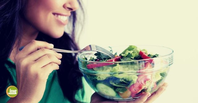 Eine junge Frau isst einen Salat. Information Mundgesundheit klärt zu gesunder Ernährung im Corona-Winter auf und fragt, was wir für ein starkes Immunsystem tun können.